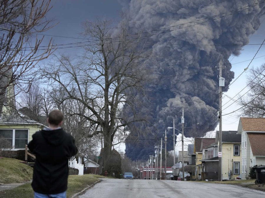 A+man+takes+photos+as+a+black+plume+rises+over+East+Palestine%2C+Ohio%2C+as+a+result+of+a+controlled+detonation+of+a+portion+of+the+derailed+Norfolk+Southern+trains+Monday%2C+Feb.+6%2C+2023.+%28AP+Photo%2FGene+J.+Puskar%29